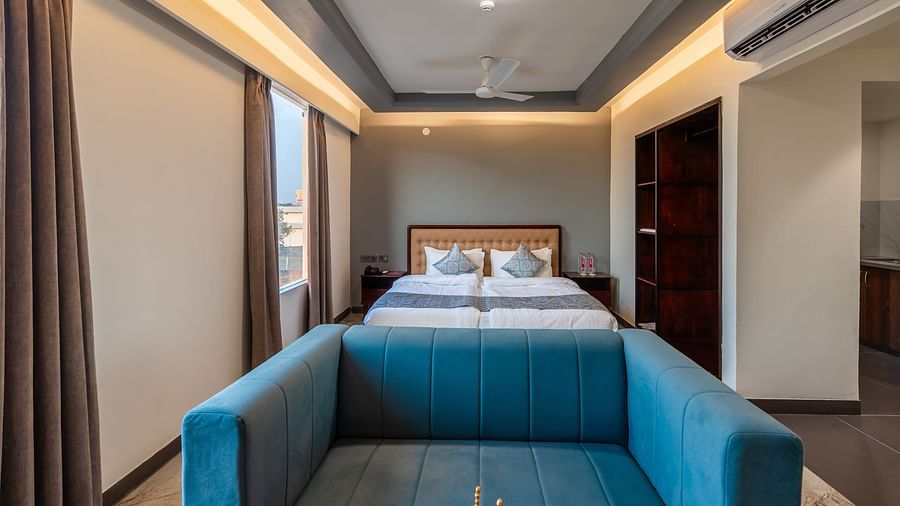 Deluxe King Room with a comfortable blue sofa and king-size bed at Clarks Inn Suites Jaipur, Ajmer Road